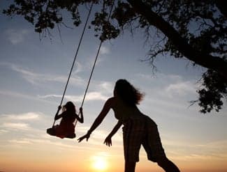 mother pushing child on swing