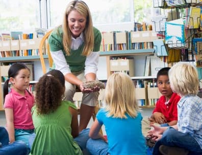 Kindergarten teacher and children looking at bird's nest in libr