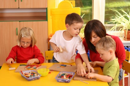 teacher and three preschoolers playing with wooden blocks