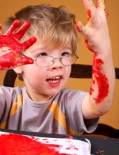 Small boy with glasses and finger paints